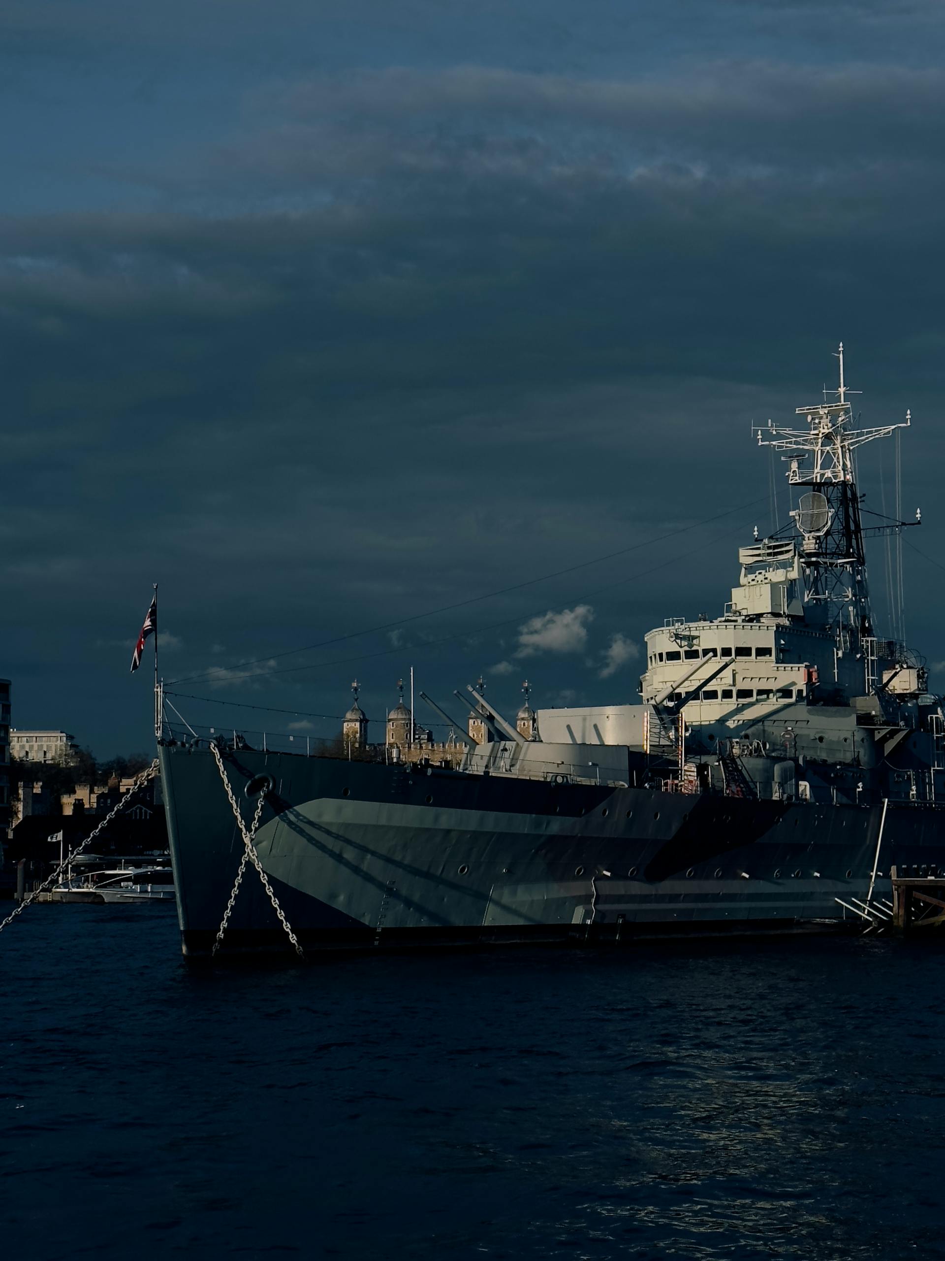 A majestic warship docked on the River Thames, showcasing military history in London.
