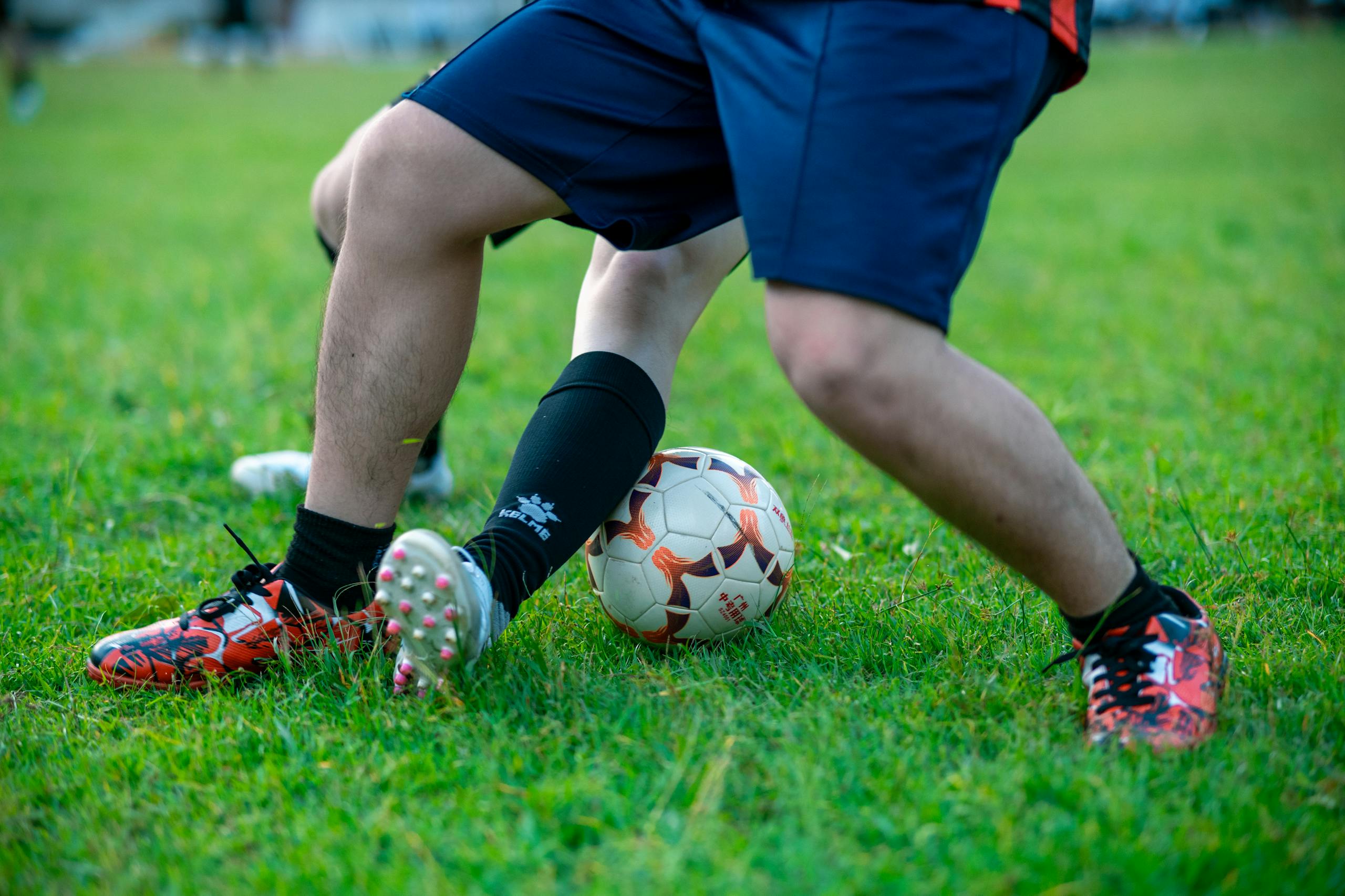 Close-up of two soccer players competing for the ball on a grassy field.